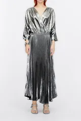 Vestido largo plateado con acabado metalizado, cuello en V cruzado, mangas 3/4 amplias y falda plisada.
