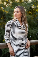 Vestido midi de punto con estampado de rayas verticales en blanco y negro, presenta un cuello drapeado y mangas largas.