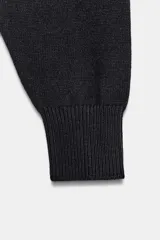 Jersey de punto liso con diseño cropped, cuello redondo y manga larga. Presenta acabados en rib en cuello, puños y bajo.