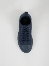 Botin de caña media con cordones, confeccionado en pana color azul marino. Presenta puntera reforzada y suela de goma con plataforma dentada del mismo tono.
