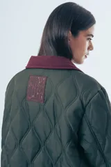 Campera acolchada de diseño matelasse con pespuntes ondulados, cuello clásico en contraste y cierre frontal con botones. Presenta bolsillos frontales con ribetes a tono y calce relajado.