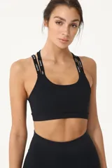 Top deportivo negro con espalda cruzada, elástico inferior y tiras regulables con logo Basset.