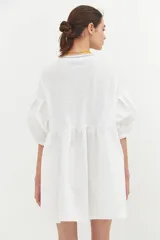 Vestido corto blanco de algodón con lurex, corte evasé, mangas cortas abullonadas y cuello redondo con ribete amarillo.