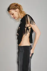 Top de cuero vacuno negro con diseño estilo navajo, caracterizado por flecos largos en todo el contorno y apliques metálicos circulares con detalles de cuentas de madera.
