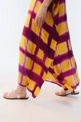 Kaftan maxi amplio de color amarillo, con escote redondo, mangas cortas y ruedo irregular. Presenta un diseño estampado a cuadros con efecto teñido.