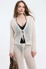 Cardigan tejido de punto calado color blanco, con mangas largas y cierre frontal con lazos.