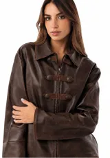 Campera estilo napoleón de cuero ovino color chocolate, con detalles de alamares y pespuntes en gamuza, y botones metálicos. Cuenta con cuello camisero, cierre frontal y mangas largas.