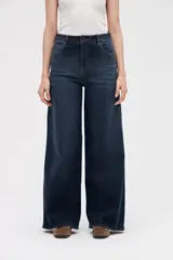Jean de corte wide leg con tiro medio, confeccionado en denim azul oscuro con lavado uniforme. Presenta diseño de cinco bolsillos, cierre frontal con botón y cremallera, y perneras amplias y holgadas desde la cadera hasta el bajo.