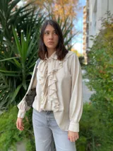 Camisa color crema de lana tejida con cuello camisero y volados frontales.