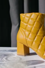 Botín de cuero celeste con diseño capitoné y taco cuadrado.