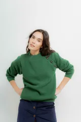 Sweater de punto en color crema con rayas horizontales en tono dorado. Presenta un diseño de cuello redondo con una solapa lateral decorada con botones metálicos dorados y corte holgado.