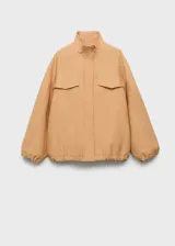 Chaqueta oversize de lyocell color beige, con cuello alto, cierre frontal oculto con botones y cremallera, bolsillos de solapa en el pecho, mangas largas con puños elásticos y bajo fruncido.