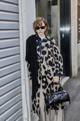 Tapado de corte recto y largo midi con estampado animal print de manchas grandes en tonos beige y negro. Presenta solapas clásicas, cierre frontal con botones y mangas largas.