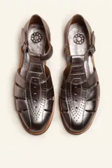 Sandalia cerrada tipo pescador de cuero negro charol, con tira en T y hebilla ajustable en el tobillo. Posee suela y taco bajo de madera.