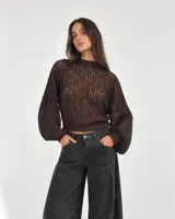 Blusa de encaje color chocolate, con cuello redondo alto, mangas largas abullonadas y puños ajustados.