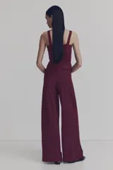 Pantalón de tiro alto color bordó, con corte holgado, piernas rectas y detalle drapeado con nudo girado en la parte frontal.