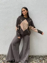 Sweater de punto con diseño de rombos en tonos gris oscuro y gris claro, de corte holgado, cuello redondo y manga larga.