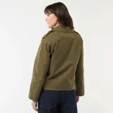 Trench corto de color verde militar, con diseño de doble botonadura, solapas anchas y trabillas en los hombros. Presenta un corte estructurado y mangas largas.
