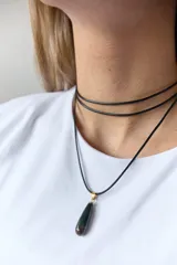 Gargantilla de cuero negro con dije de piedra blanca en forma de lágrima con engarce dorado.