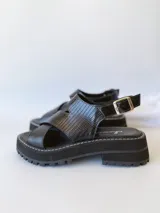 Sandalias negras de cuero con tiras cruzadas, plataforma track y hebilla lateral.