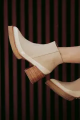 Botín de cuero color beige con puntera charolada, cierre lateral con cremallera y tacón ancho de madera.