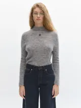 Polera azul de tejido suave con cuello alto y manga larga. Tiene un pequeño bordado en el frente y otro en la manga.