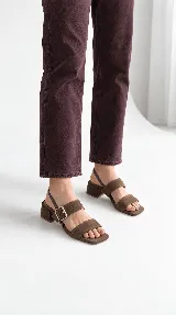 Sandalias de cuero color marrón chocolate, con taco cuadrado de 4 cm, diseño de dos tiras frontales y tira ajustable con hebilla en el talón.