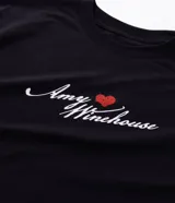 Remera boxy fit de algodón color negro, con cuello redondo y mangas cortas. Presenta un estampado de la cantante Amy Winehouse en blanco y negro con detalles en rojo, y la inscripción "Amy Winehouse Back to Black".