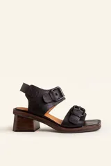 Sandalias de cuero negro con taco bloque de madera tallada, tiras con hebillas grandes y punta cuadrada.