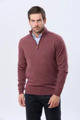 Buzo de tejido fino en hilo de algodón, color rosado, con cuello alto y cierre frontal parcial con detalle en cuero. Presenta puños y ruedo acanalados y un pequeño logo bordado en el pecho.