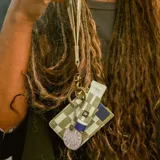 Llavero de muñeca con cinta de tela estampada a cuadros en tonos verde y blanco, con aplique de cuero sintético verde y gancho metálico color bronce.