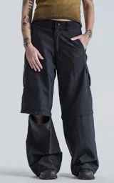 Pantalón cargo negro convertible, con cierre en la parte media de la pierna que permite transformarlo en un short ancho. Presenta bolsillos cargo a los lados y un corte holgado.