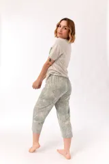 Conjunto de pijama de algodón color champagne, compuesto por una remera de manga corta con cuello henley y bolsillo en el pecho, y un pantalón capri a rayas horizontales celestes y blancas.