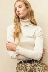 Polera de tejido fino color negro, con cuello alto y mangas largas con terminación sutilmente fruncida. Diseño ajustado al cuerpo.