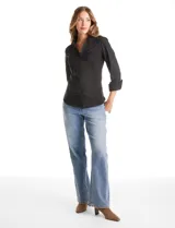 Camisa entallada de color negro con pechera estructurada mediante alforzas horizontales. Presenta cuello con solapa, escote en V, cierre frontal con botones y mangas tres cuartos con puños anchos rebatibles.