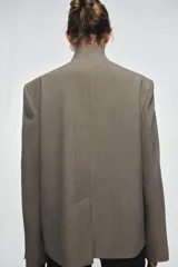 Blazer de cuello subido con cierre frontal cruzado de botones. Presenta manga larga con hombreras y puños con botones, bolsillos de vivo en el delantero y forro interior.