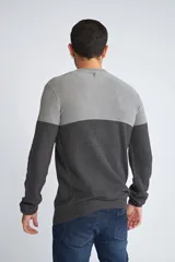 Sweater de punto con diseño color block en tonos gris claro y gris oscuro, de cuello redondo y manga larga. Presenta un pequeño logo bordado en el pecho.