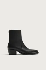 Bota de piel color negro con acabado abatanado, caña corta, punta fina y tacón cuadrado a tono.