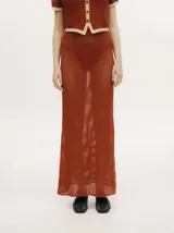 Conjunto de tejido calado color azul petróleo con detalles en amarillo. Incluye un cárdigan corto con botones y una falda larga recta con pretina elástica.