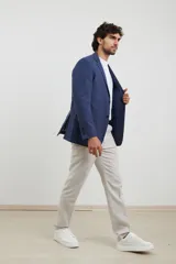Saco azul de lino, de corte clásico, con solapa de muesca, cierre de dos botones, bolsillos frontales con solapa y aberturas traseras.