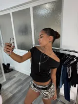 Top negro con escote asimétrico y manga corta.