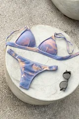 Bikini de dos piezas color marrón, con corpiño triangular fijo con corte bajo el busto, breteles regulables con hebilla y almohadillas desmontables. La bombacha es vedetina con frunce elástico en los costados.