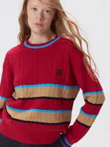 Sweater de punto cable con diseño a rayas horizontales en colores rojo, beige, negro y azul. Presenta cuello redondo acanalado, mangas largas con puños ajustados y logo bordado en el pecho.