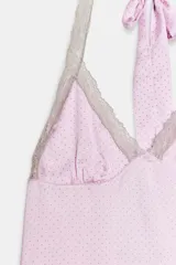 Top de satén rosado con estampado de lunares, escote en V y cuello halter con lazo para atar. Presenta detalles de encaje en contraste a lo largo del escote y los tirantes.
