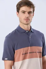 Remera polo de manga corta con diseño en bloques de color en tonos azul marino, blanco y verde militar, con bordado frontal y cierre de botones.