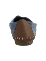 Zapatos slip-on de cuero gamuzado color azul, con detalles de tachas metálicas en el empeine y costuras expuestas con borde marrón.