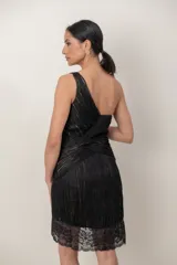 Vestido corto negro confeccionado en gasa drapeada sobre seda natural, con diseño asimétrico de un solo hombro. Presenta detalles de bordado artesanal con lentejuelas y piedras, y terminación de encaje en el ruedo de la falda.