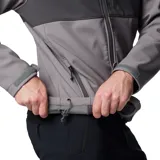Chaqueta Columbia Ascender Soft Shell con diseño bicolor en tonos gris y gris oscuro. Cuenta con cierre frontal completo, cuello alto con protector de mentón, bolsillo en el pecho con cierre, bolsillos laterales con cierre y puños ajustables con velcro.