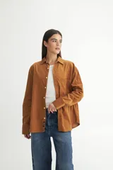 Camisa color marrón confeccionada en tela de algodón con cuello solapa clásico, bolsillo cuadrado en pecho, botones personalizados y tela de pana fina. Calce oversize.