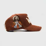 Gorra tipo trucker de pana color marrón, con bordado frontal en relieve y detalle lateral bordado del Sagrado Corazón de Jesús.